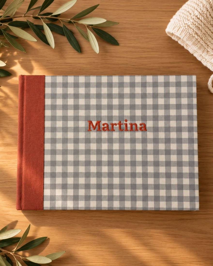 Álbum de fotos personalizado con el nombre «Martina» bordado y lomo teja, sobre una mesa de madera