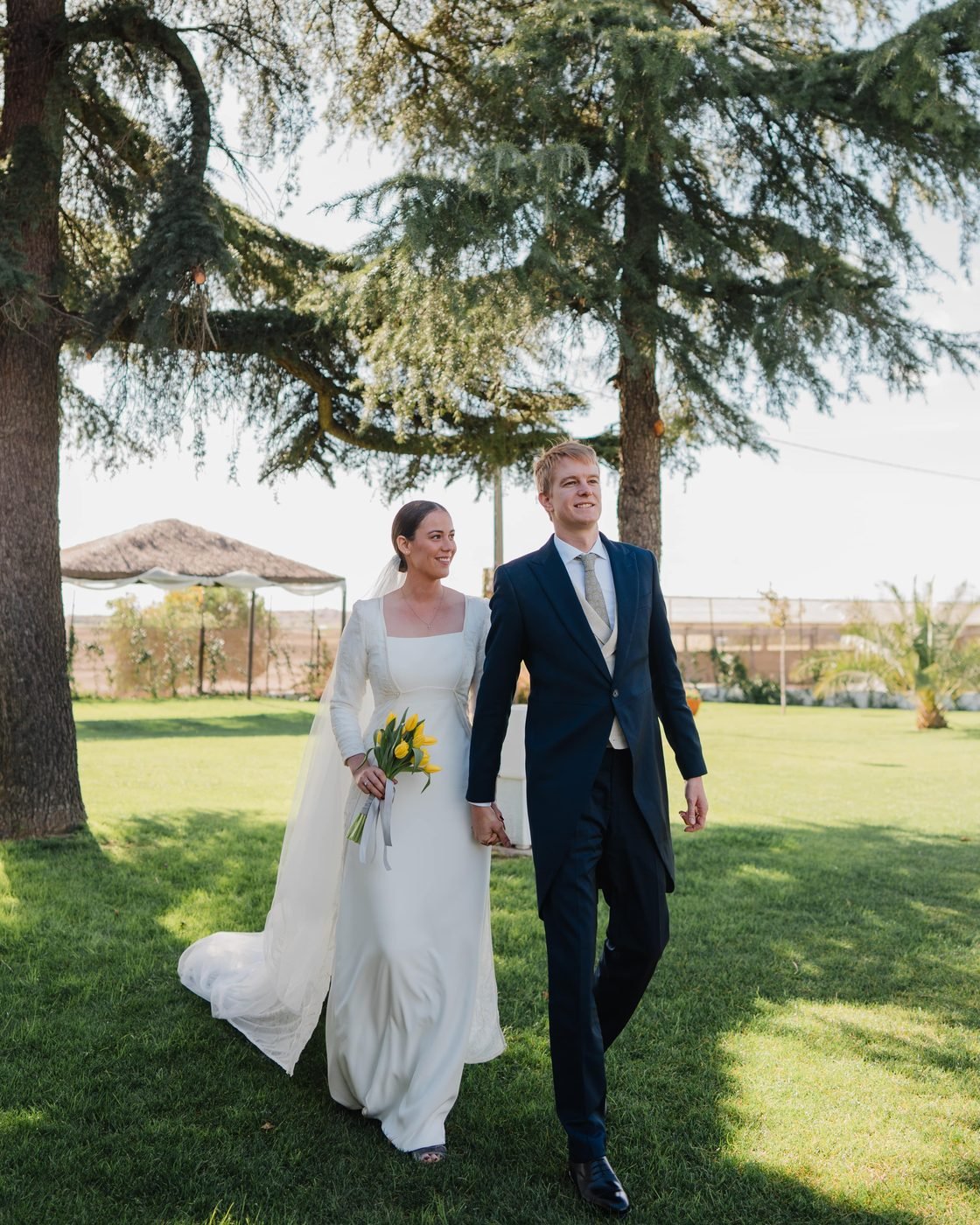 Patrizia y su marido el día de su boda, paseando de la mano por un jardín
